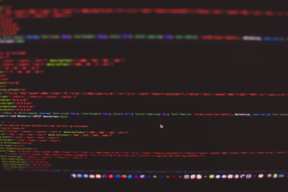 A close-up photograph of a computer screen displaying lines of colorful code, including HTML and CSS elements, on a dark background. The code features various syntax with red, green, blue, and purple